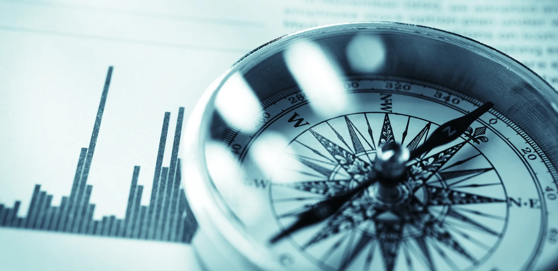 A black and white image of a compass on top of a bar chart.