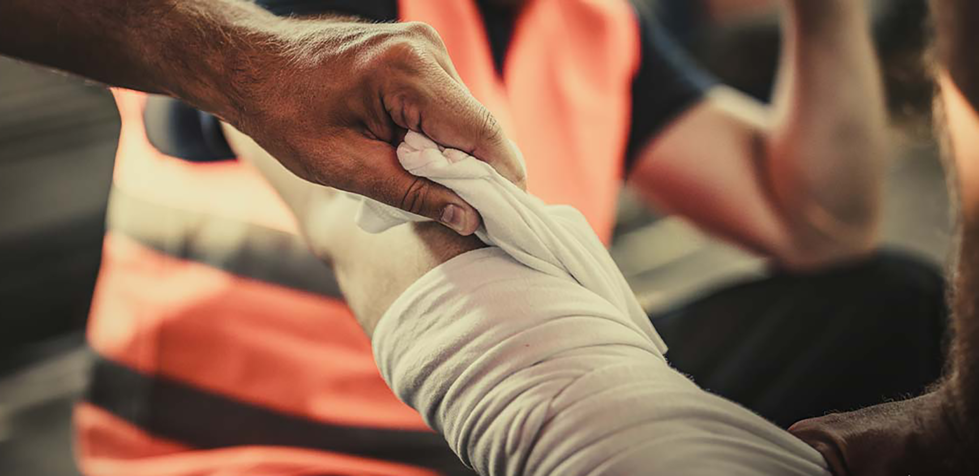 A contractor wearing an orange vest getting their arm wrapped.