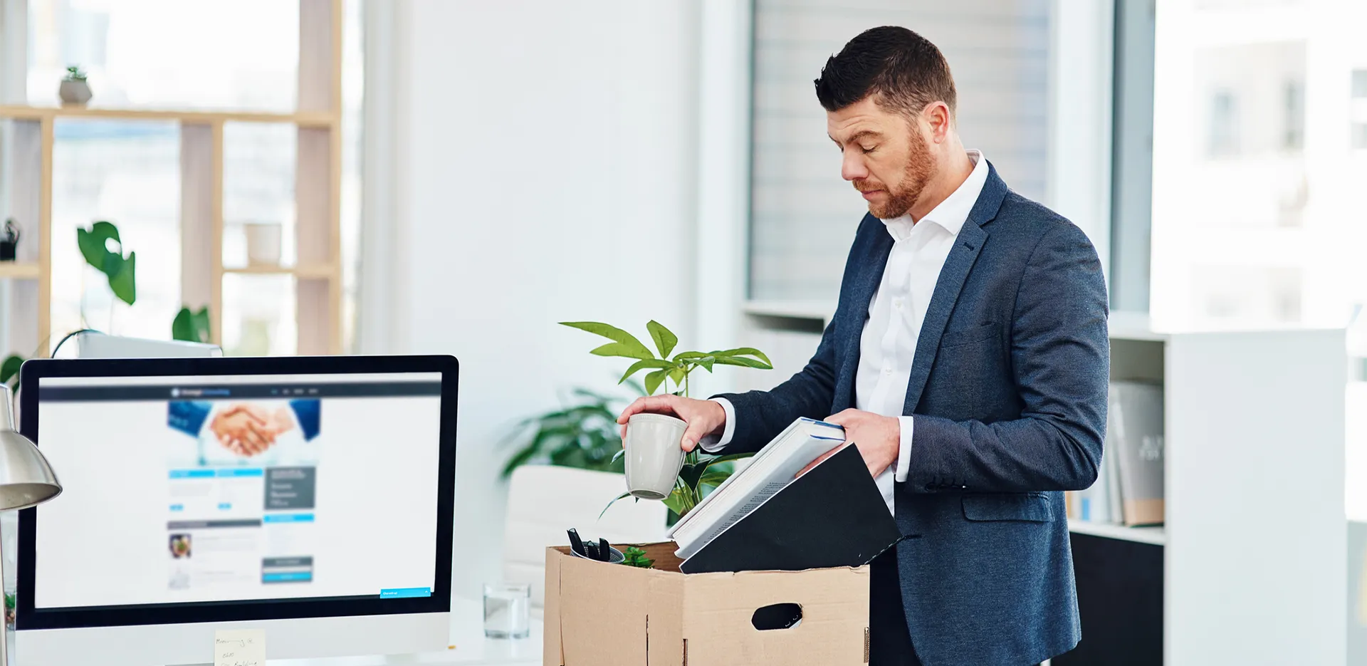A businessman packing his desk up in a cardboard box.