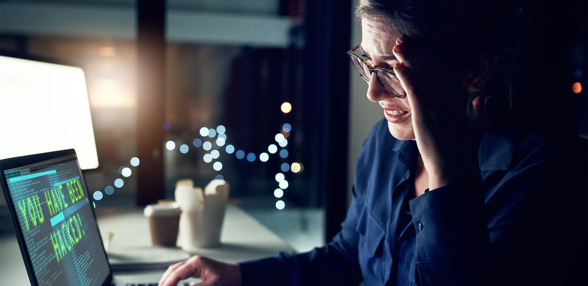 A woman looking with frustration at a computer screen, which reads 'you have been hacked!'