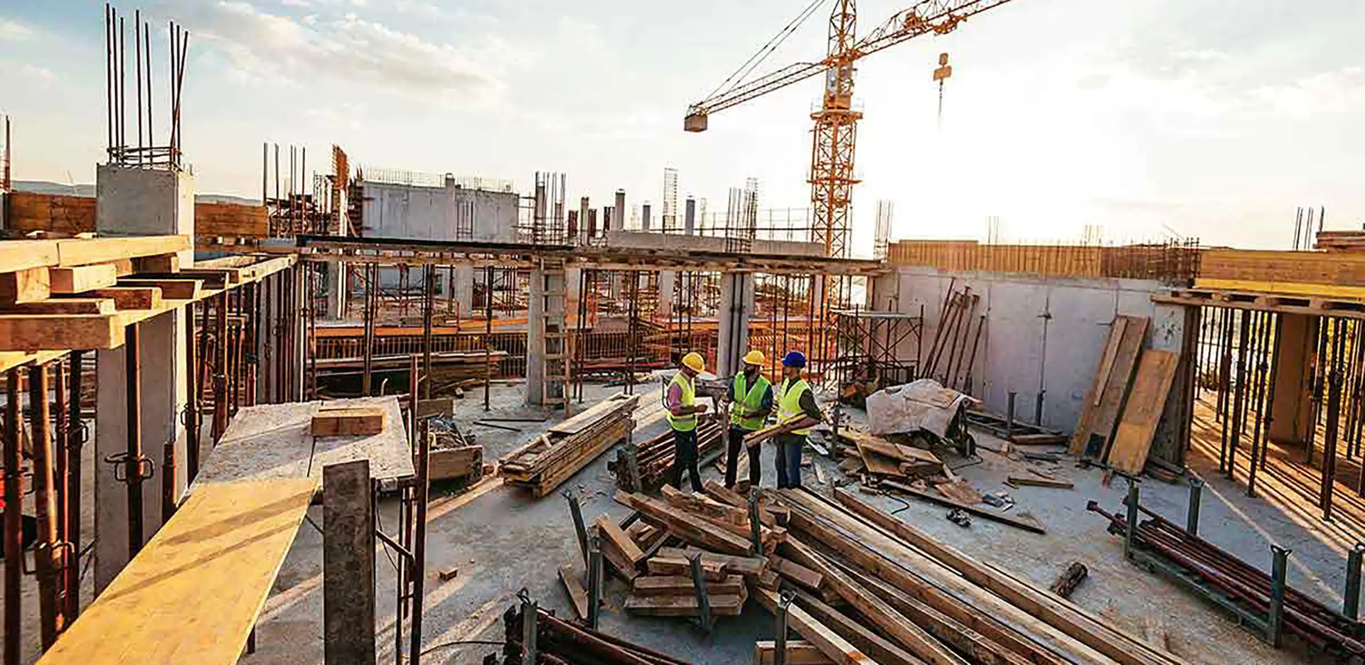 A trio of construction workers standing on a rooftop that's under construction.
