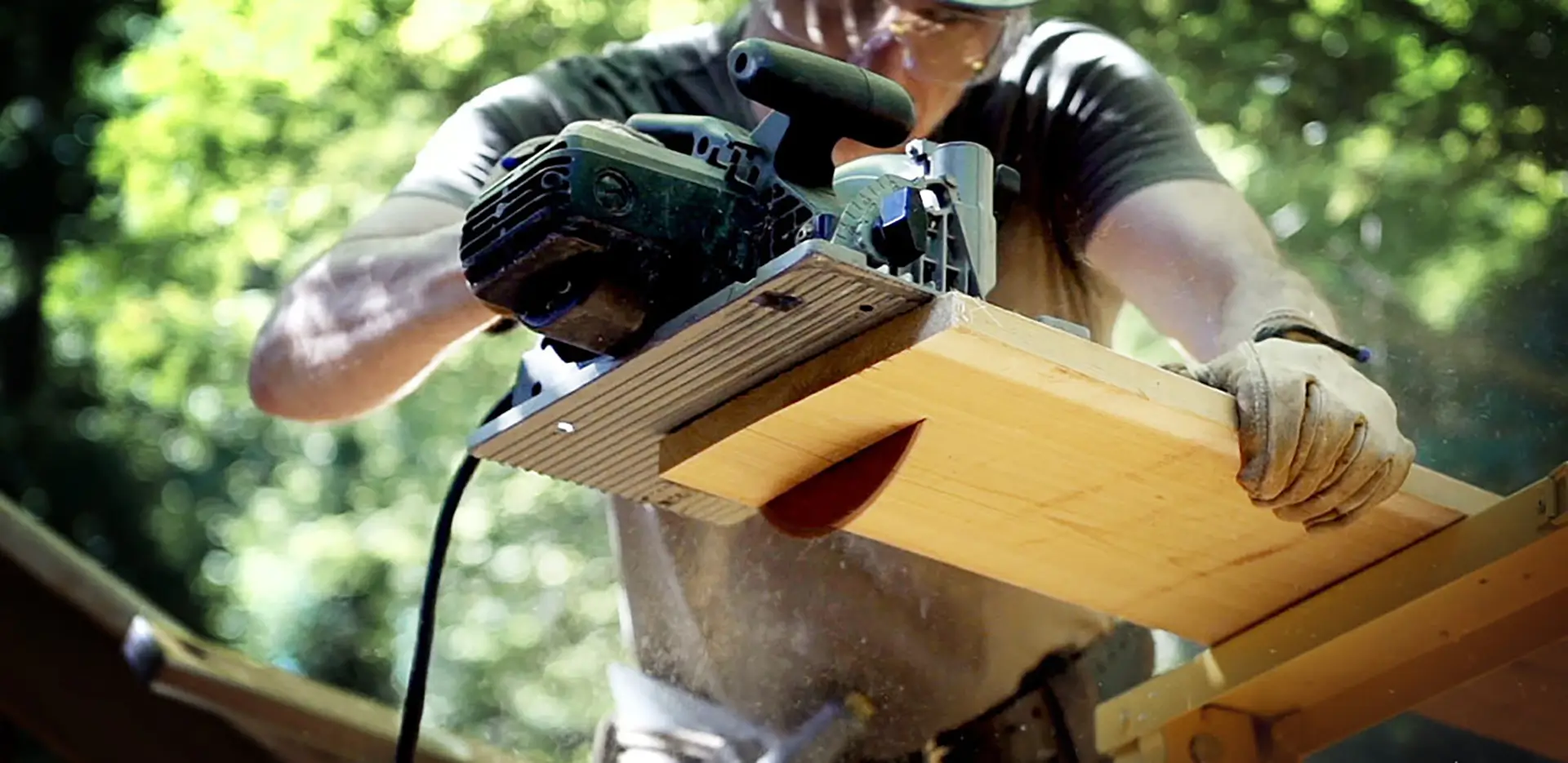 Someone cutting a wooden board with a circular saw.