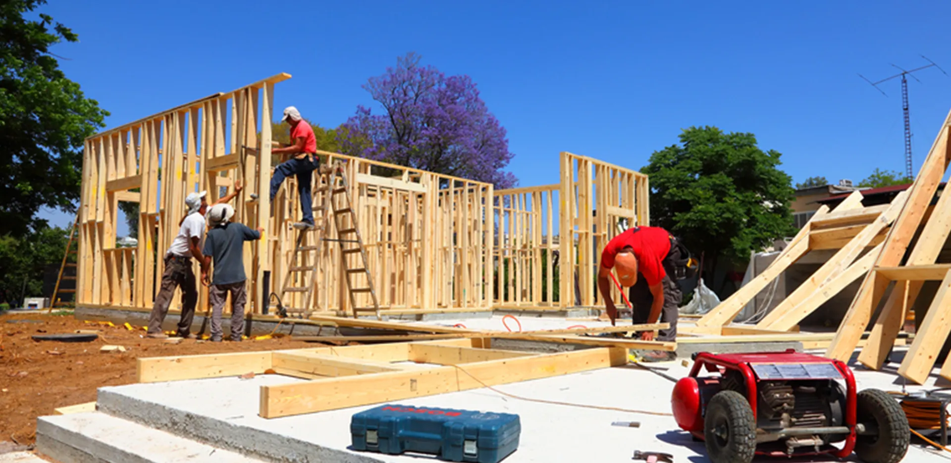 A construction site with wood framing being erected by construction workers.