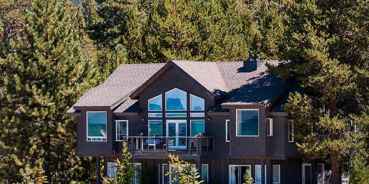 An exterior shot of a two-story home painted black and surrounded by trees.