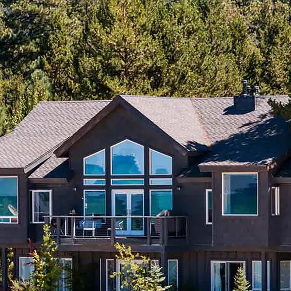 An exterior shot of a two-story home painted black and surrounded by trees.
