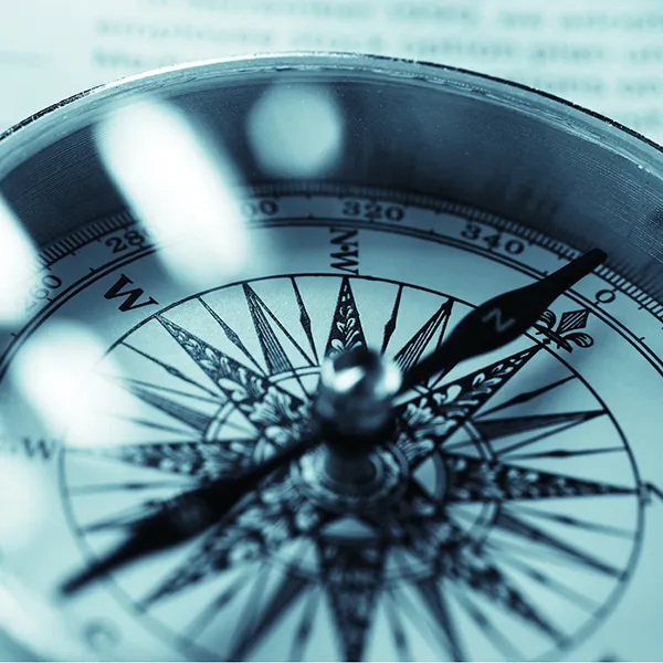 A black and white image of a compass on top of a bar chart.