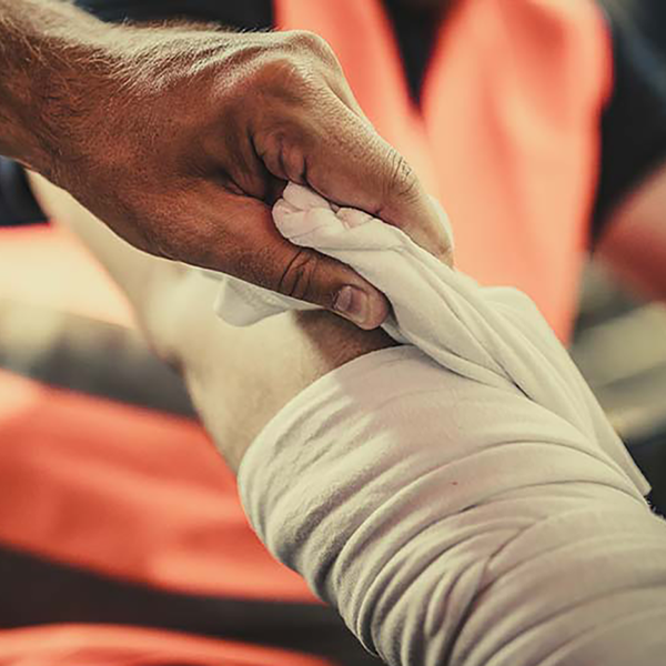 A contractor wearing an orange vest getting their arm wrapped.