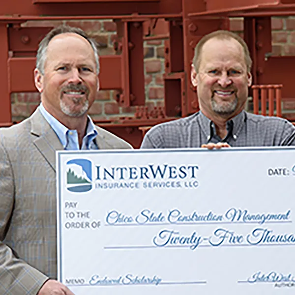 A group of InterWest team members standing with a large check representing a donation to CSU Chico.