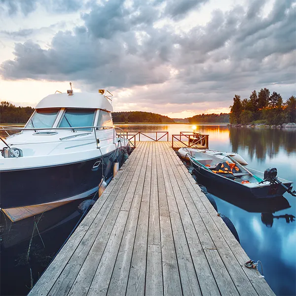 Two boats tied to a wooden dock on a lake.