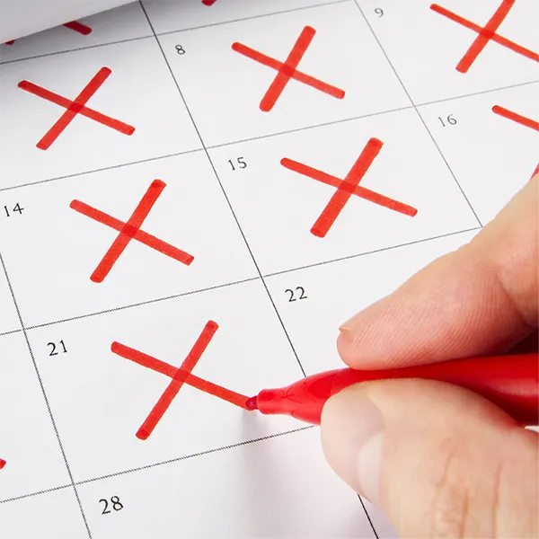 Someone crossing days off of a calendar in red pen.