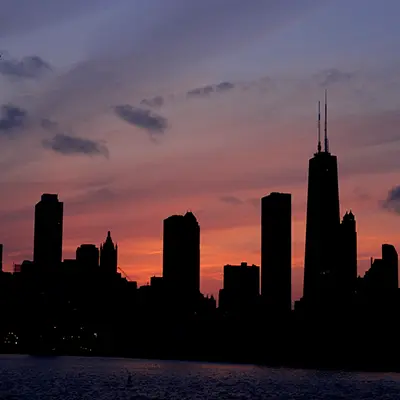 A dark city skyline at dusk with skyscrapers dark and unlit.