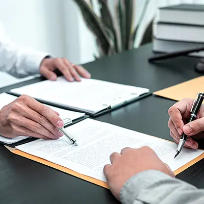 Two people looking over paperwork on a desk.