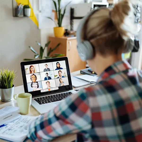 A person taking a video call at home with their cat sitting on their desk.