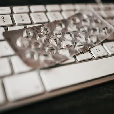 An empty pill blister pack sitting on top of a computer keyboard.