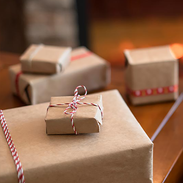 Someone shopping on their computer with a credit card with wrapped gifts next to them.