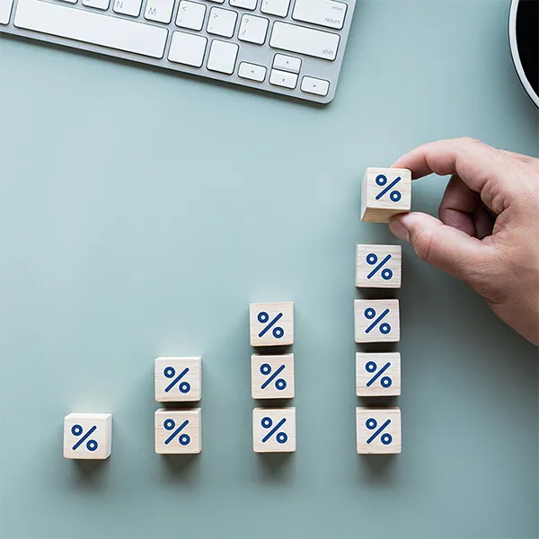 A hand stacking wooden blocks with percentage signs on them.