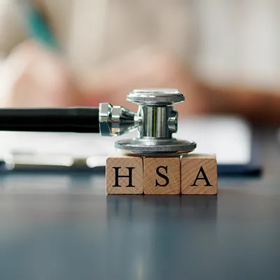A stethoscope sitting on top of three wood blocks with the letters H, S, and A printed on them.