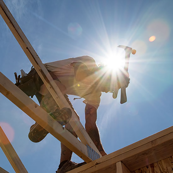 A construction worker working on the wooden frame of a house.