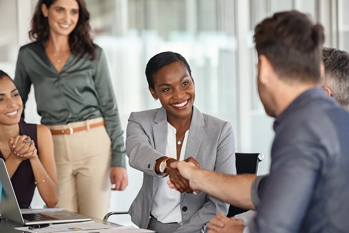 a woman and man shaking hands with other people looking on