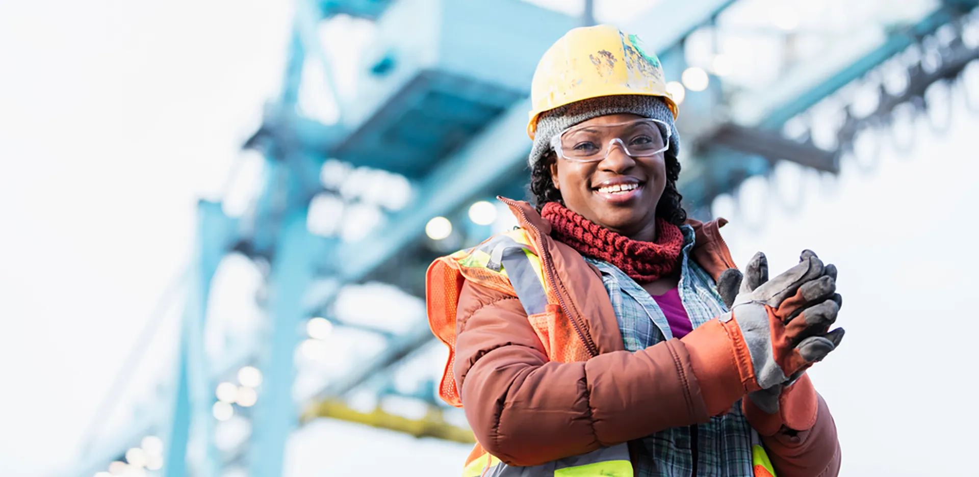 A construction worker dressed for winter weather wearing a hard hat and gloves.