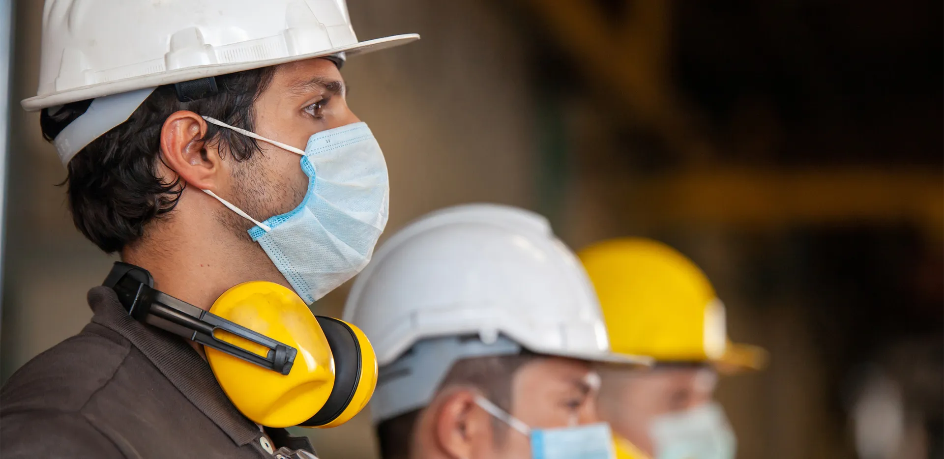A line of construction workers wearing hard hats and masks.
