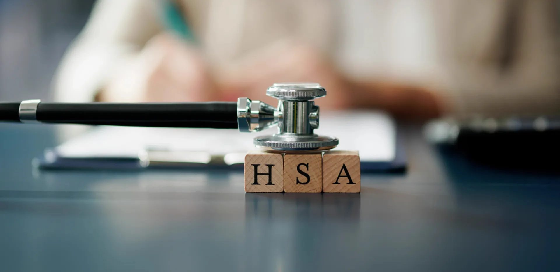 A stethoscope sitting on top of three wood blocks with the letters H, S, and A printed on them.